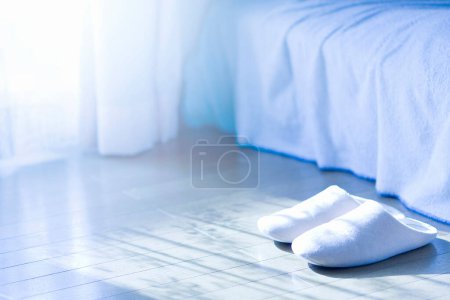 Téléchargez les photos : Pantoufles blanches et un lit par une matinée ensoleillée - en image libre de droit