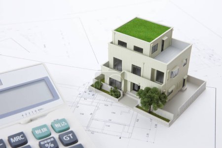 Photo for Model of house with calculator and blueprints on table. real estate concept - Royalty Free Image