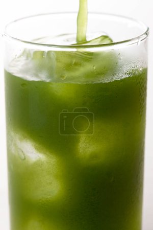 Téléchargez les photos : Vue rapprochée du verre de thé vert matcha glacé sur fond clair - en image libre de droit
