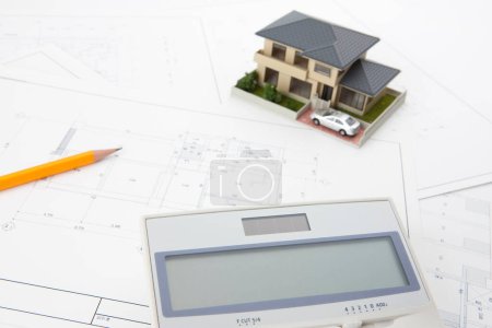 Foto de Modelo de casa con calculadora y planos sobre mesa. concepto de bienes raíces - Imagen libre de derechos