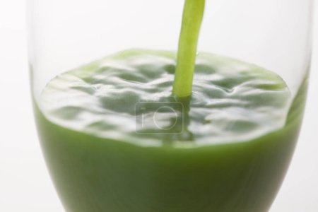 Téléchargez les photos : Vue rapprochée de vert fraîche boisson biologique saine verser dans le verre sur fond clair - en image libre de droit