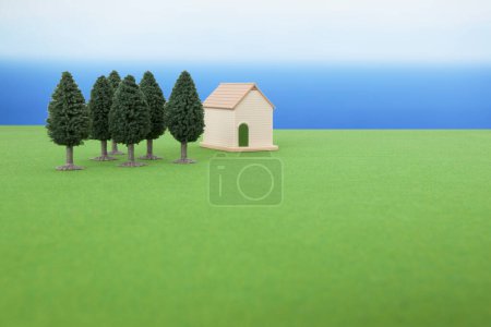 Photo for Miniature house model and green trees on grassy meadow. - Royalty Free Image