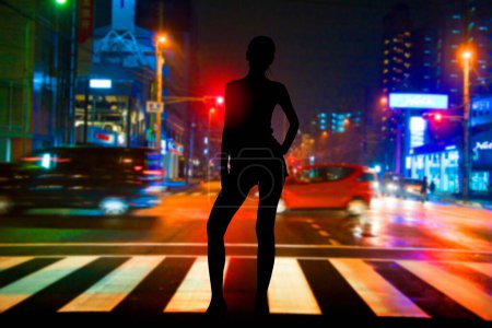 Photo for A woman standing on a crosswalk at night - Royalty Free Image