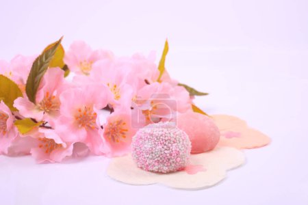 Photo for Close-up view of delicious japanese sweets and pink blossoms on light background - Royalty Free Image