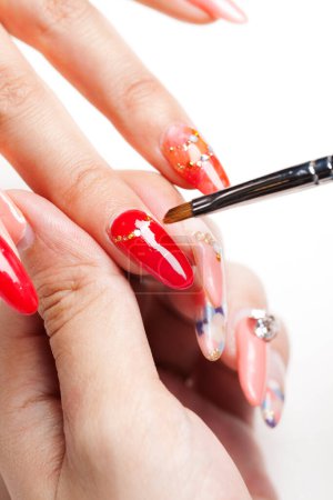 Foto de Manicura roja en uñas femeninas sobre un hermoso fondo - Imagen libre de derechos