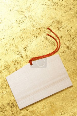 Foto de Tarjeta de etiqueta en blanco con cuerdas rojas sobre fondo dorado - Imagen libre de derechos