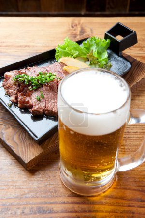 Téléchargez les photos : Un steak et une bière sur une table - en image libre de droit