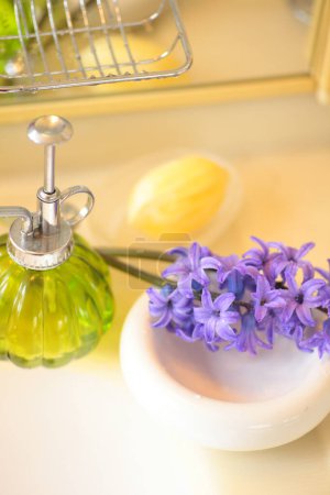 Foto de Hermosas flores moradas con botella de jabón en el baño - Imagen libre de derechos