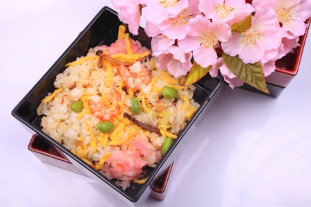 Téléchargez les photos : Cuisine japonaise. délicieux riz aux crevettes et légumes et fleurs roses de printemps sur fond clair - en image libre de droit