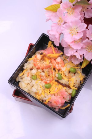 Téléchargez les photos : Cuisine japonaise. délicieux riz aux crevettes et légumes et fleurs roses de printemps sur fond clair - en image libre de droit