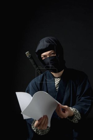 Photo for Young man in a ninja outfit holding an envelope - Royalty Free Image