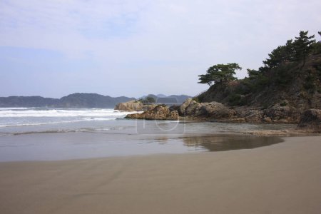 Foto de Una playa con una roca y un cuerpo de agua - Imagen libre de derechos