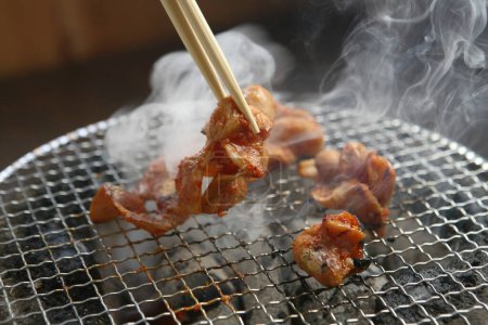 Photo for A close up shot of frying meat on grill  with chopsticks - Royalty Free Image