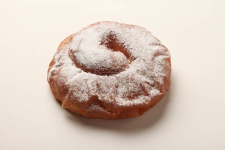 Téléchargez les photos : Un beignet recouvert de sucre en poudre sur une surface blanche - en image libre de droit