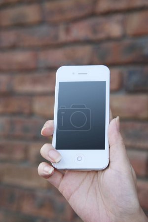 Téléchargez les photos : Les mains de la femme tenant le téléphone portable avec écran blanc - en image libre de droit