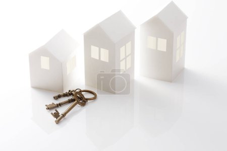 Foto de Vista de cerca de las llaves y casas modelos sobre fondo blanco. concepto de bienes raíces - Imagen libre de derechos