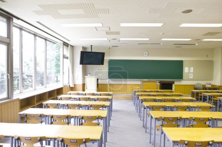 Photo for Interior of empty classroom with green blackboard on wall. Rows of wooden desks and chairs - Royalty Free Image