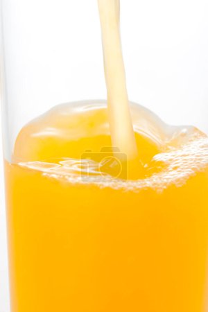 Téléchargez les photos : Vue rapprochée de verser du jus d'orange en verre sur fond blanc - en image libre de droit
