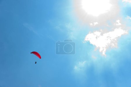 Téléchargez les photos : Parachute rouge volant dans le ciel bleu - en image libre de droit
