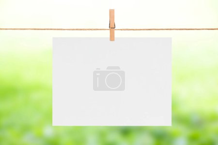 Foto de Hoja en blanco de papel colgando de la cuerda de la ropa, fondo borroso verde verano - Imagen libre de derechos