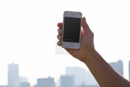 Photo for Cropped shot of person holding smartphone with blank screen on urban background - Royalty Free Image