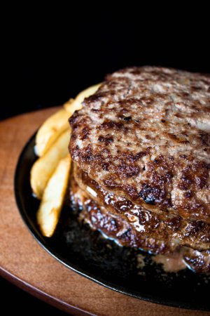 Téléchargez les photos : Steaks grillés avec frites dans une assiette noire - en image libre de droit
