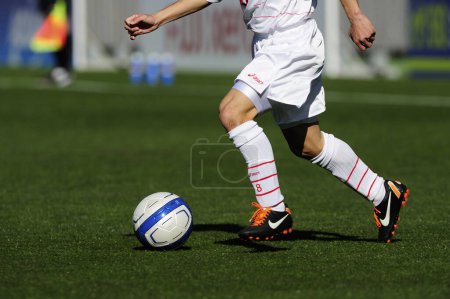 Foto de Piernas de jugador de fútbol en ropa deportiva jugando con la pelota en la hierba - Imagen libre de derechos