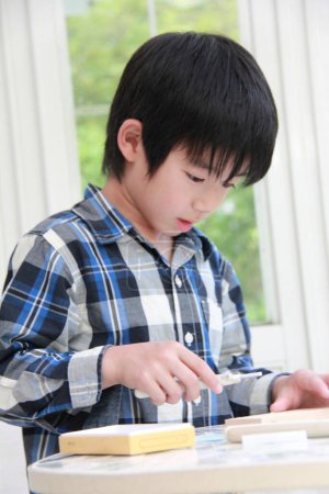 Téléchargez les photos : Preteen asiatique garçon jouer avec en bois blocs à la maison - en image libre de droit