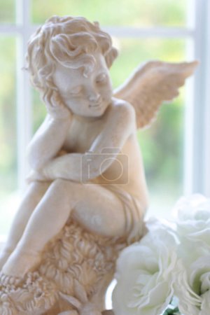 Foto de Hermosa pequeña figura de ángel en un alféizar de ventana, decoración casera de estilo antiguo - Imagen libre de derechos