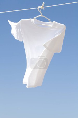 Téléchargez les photos : Une chemise blanche pend à nouveau fond bleu ciel. - en image libre de droit