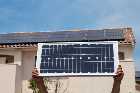 Foto de Manos sosteniendo el panel de energía solar sobre el cielo azul - Imagen libre de derechos