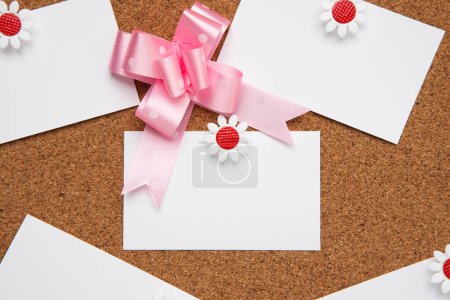 Photo for Pink bow made of ribbon and blank business cards pinned on cork board - Royalty Free Image