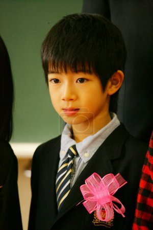 Photo for Cute preteen Japanese boy in school wearing suit decorated with pink bow - Royalty Free Image