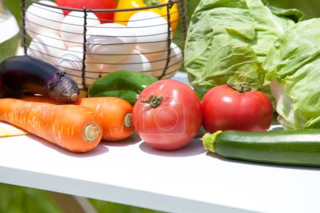Foto de Verduras frescas y huevos en una canasta de mimbre en la mesa al aire libre - Imagen libre de derechos
