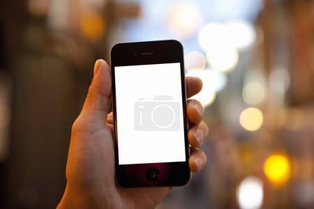 Foto de Recortado de la persona que sostiene el teléfono inteligente con pantalla en blanco ob fondo borroso - Imagen libre de derechos