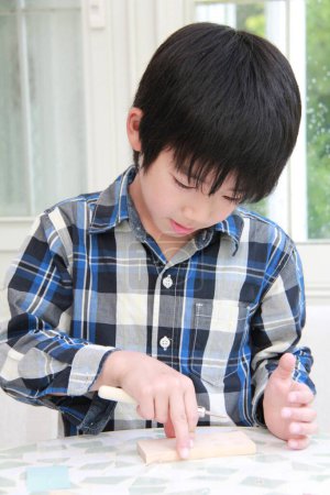 Photo for Preteen Asian boy playing with wooden blocks at home - Royalty Free Image