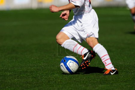 Photo for Legs of sports people in sportswear playing soccer on grass - Royalty Free Image