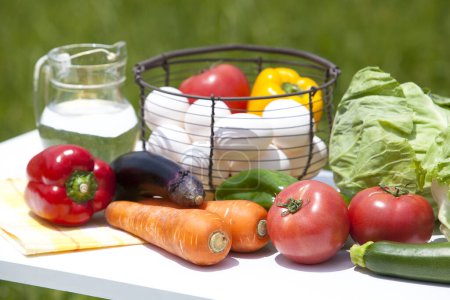 Téléchargez les photos : Légumes frais et oeufs dans un panier en osier sur la table à l'extérieur - en image libre de droit