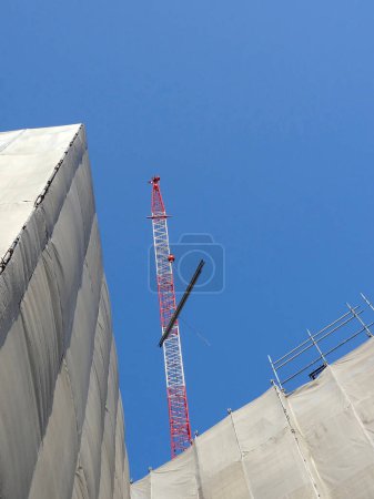 Téléchargez les photos : Une grue sur le dessus d'un bâtiment avec un ciel bleu en arrière-plan - en image libre de droit