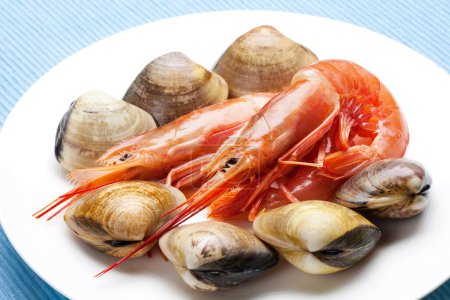 Téléchargez les photos : Une assiette de fruits de mer et de palourdes sur une nappe bleue - en image libre de droit