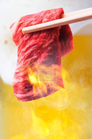 Téléchargez les photos : Un morceau de viande cuit avec des baguettes - en image libre de droit