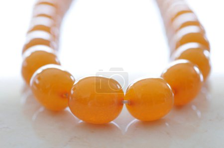 Téléchargez les photos : Un collier de perles jaunes sur une surface blanche - en image libre de droit