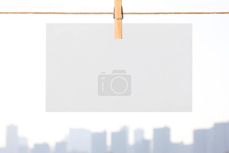 Foto de Hoja en blanco de papel colgado en la cuerda de la ropa contra el horizonte del paisaje urbano - Imagen libre de derechos