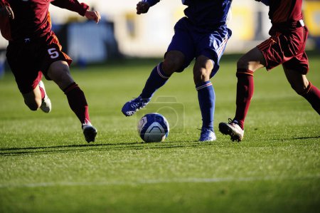 Téléchargez les photos : Jambes des joueurs de football en vêtements de sport jouer avec le ballon sur l'herbe - en image libre de droit