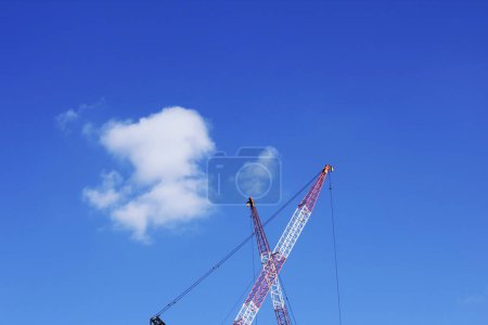 Téléchargez les photos : Vue à angle bas des grues du chantier sur fond de ciel bleu - en image libre de droit