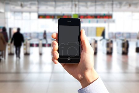 Foto de Imagen recortada de la persona que sostiene el teléfono inteligente con pantalla en blanco en el fondo borrosa estación de tren - Imagen libre de derechos