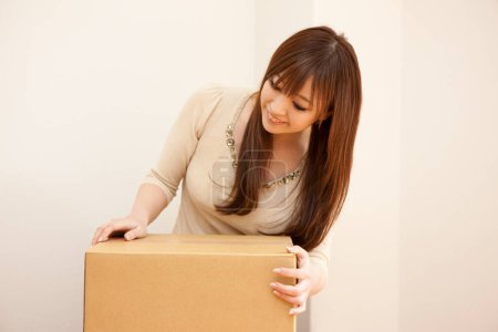 Téléchargez les photos : Femme portant boîte en carton à la maison - en image libre de droit