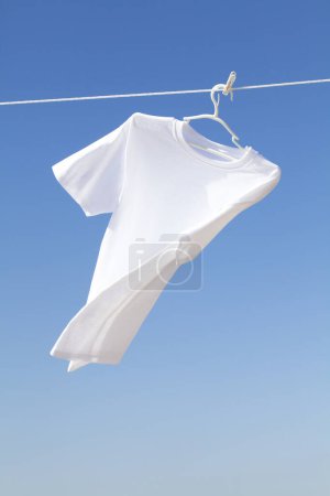 Foto de Una camisa blanca cuelga contra fondo azul cielo. - Imagen libre de derechos