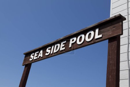 Téléchargez les photos : Le signe de la piscine côté mer contre le ciel bleu - en image libre de droit
