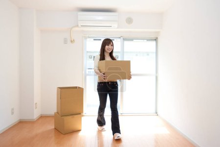 Photo for Young woman holding a box in the living room - Royalty Free Image